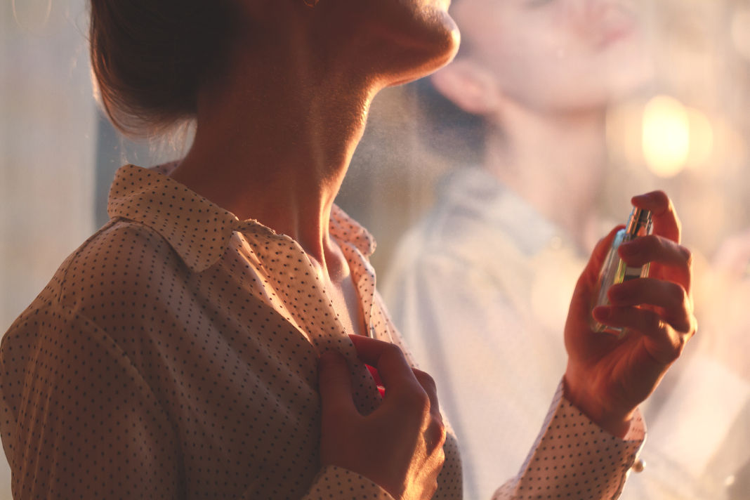 Parfum à Marseille femme en chemise se vaporisant une bouteille de parfum