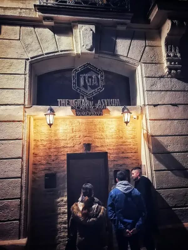 un groupe d'amis devant la porte d'entrée du Grand Asylum escape game à Montpellier